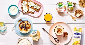 Ontbijtset met Campina milde kwark, Biologische Skyr, Alpro yoghurt drink, knäckebröd met verse kaas, passievrucht en granola.