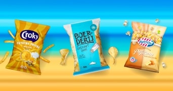 Drie verpakkingen snacks: Croky Patatas Fritas, Boerderij Zeezout Chips en Jimmy's Cinema Style Popcorn Caramel & Cheese op een strandachtergrond.