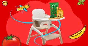 Kindertstoel met Ella's Kitchen snackpakket en fruitsmoothie op een kleurrijke achtergrond met getekende groenten en fruit.