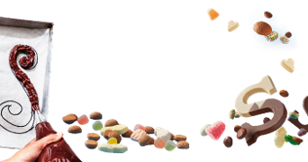 Decoreren van chocoladetekens en snoepjes op bakpapier met kleurrijke decoraties, waaronder gekleurde suikergoed en chocoladeswirls.