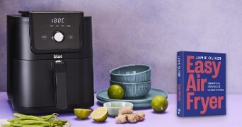 Airfryer naast Jamie Oliver's kookboek "Easy Air Fryer", met limoen, gember en sperziebonen op de voorgrond.
