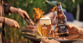 Hertog Jan Grand Pilsener flesje en glas bij een barbecue.