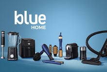 Verschillende huishoudelijke apparaten van het merk Blue, waaronder een blender, staafmixer, airfryer, haardroger, krulborstels, stofzuiger en strijkijzer, tegen een blauwe achtergrond met de tekst "blue HOME".