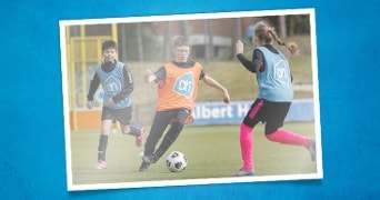 Kinderen spelen voetbal op een sportveld met hesjes van Albert Heijn