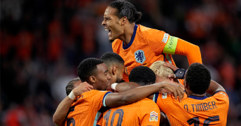 Voetbalspelers van het Nederlands elftal vieren samen een doelpunt tijdens een wedstrijd, gekleed in oranje shirts met rugnummers.