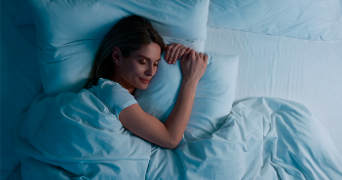 Vrouw slapend in bed met lach op haar gezicht