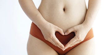 Persoon in ondergoed met handen in de vorm van een hart boven de buik.