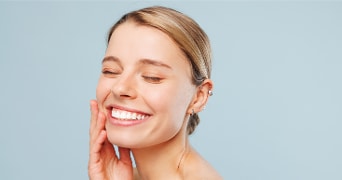 Vrouw met blonde haren en oorpiercings op een blauwe achtergrond