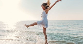 Vrouw in een witte jurk geniet van de zee op een zonnige dag