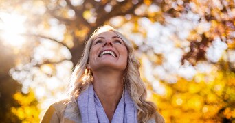 Vrouw onder herfstkleurige bomen.