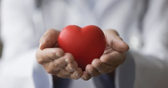 Hands die een rood hartvormig object vasthouden