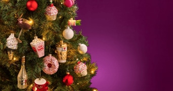 Kerstboom versierd met unieke kerstballen, waaronder popcorn, koffie en cupcakes.