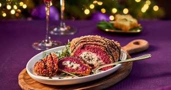 Vegetarische wellington met biet en champignonragout geserveerd op een wit bord met feestelijke achtergrond