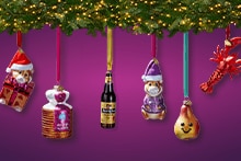 Kerstboom met kerstballen in de vorm van avocado, teddybeer met kerstmuts, stroopwafelblik, flesje Hertog Jan bier, teddybeer in paarse kleding, lachende peer, kreeft en kleurrijk koekje, versierd met lichtjes