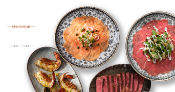 Schotels met rauwe zalm, carpaccio van rundvlees, gegrilde garnalen en plakjes biefstuk, gepresenteerd op sierlijke borden.