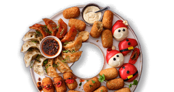 Tapas schaal met diverse snacks zoals gyoza met dipsaus, kroketjes en feestelijke broodjes in de vorm van kerstmannen