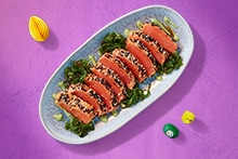 Verschillende kleurrijke paastraktaties op een tafel, waaronder een croissantkrans, mini stolletjes en zalm tataki