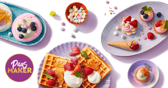 Assortiment van kleurrijke paasdesserts, waaronder wafels met slagroom en aardbeien, meringues met fruit, mini taartjes met bessen, en een hoorntje met framboos, gepresenteerd op verschillende borden. Paasmaker logo linksonder.