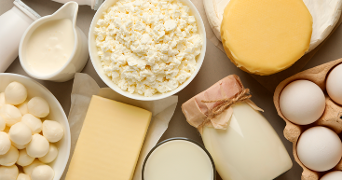 Verschillende zuivelproducten waaronder melk, eieren, kaas, cottage cheese, room en mozzarella op een tafel.