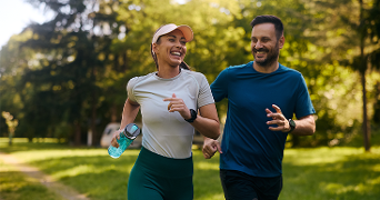 Twee mensen rennen samen buiten in een groen park, sportief gekleed en met een waterfles in de hand