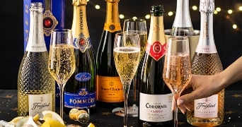 Assortiment van mousserende wijnen, waaronder Freixenet Prosecco, Pommery Brut, Veuve Clicquot Brut, Codorníu Clásico, en Freixenet Italian Rosé, met glazen gevuld met champagne en prosecco op de voorgrond.