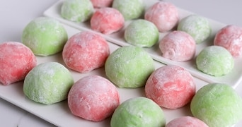 Groene en roze mochi op een witte schaal