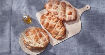 Vers gebakken platbrood op houten snijplank met olijfolie.