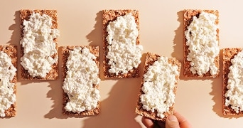 Volkoren crackers belegd met cottage cheese.