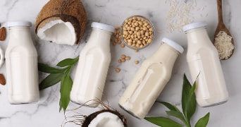 Plantaardige melk in flessen, gemaakt van kokosnoot, soja, amandelen en rijst op een marmeren achtergrond.