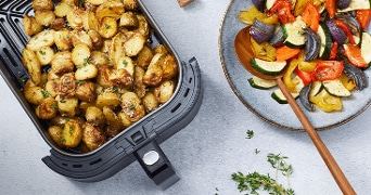 Geroosterde aardappelen en gegrilde groenten in een Airfryer en op een bord.