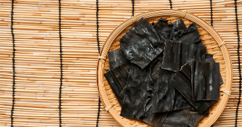 Gedroogde kombu zeewier in een ronde mand op een bamboemat