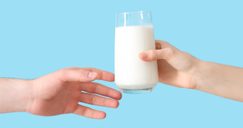 Twee handen die een glas melk doorgeven voor een blauwe achtergrond.