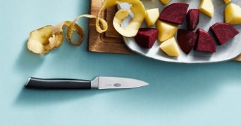 Gesneden rode bieten en geschilde aardappelen op een snijplank met een keukenmes.