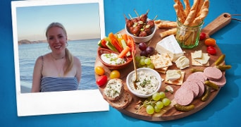 Borrelplank met diverse hapjes zoals kaasblokjes, druiven, crackers, smeersels en groenten.