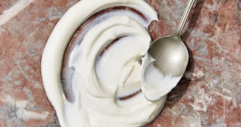 Griekse yoghurt uitgespreid met een lepel op een marmeren oppervlak