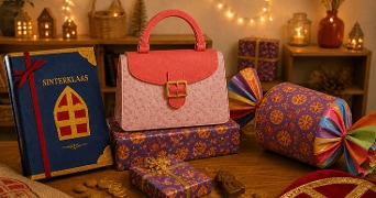 Sinterklaasboek, cadeautjes in feestelijk papier, schuimpjes, chocolade munten en een roze handtas van marsepein op een houten tafel, met sfeervolle verlichting op de achtergrond.