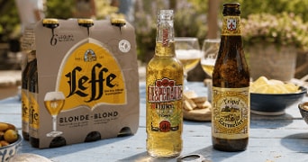 Leffe Blonde bier verpakking, Desperados Original fles en Tripel Karmeliet fles op een tafel met snacks.