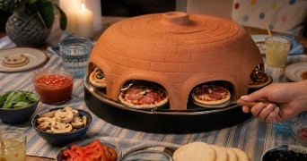 Pizzarette op tafel met allemaal zelgemaakte mini pizza's. Op tafel ook toppings.