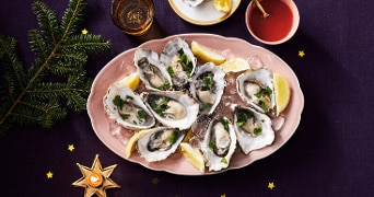 Plateau met verse oesters geserveerd op ijs met partjes citroen, decoratief opgediend op een feestelijke tafel