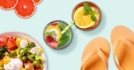 Zomers tafereel met frisse salade, citrusvruchten drankjes en oranje teenslippers.