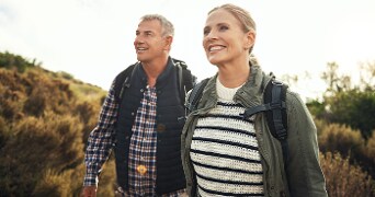 Twee mensen met rugzakken wandelen in een natuurlijke omgeving.
