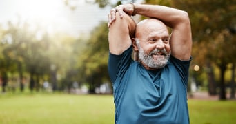 Man in sportkleding rekt zijn arm in een park