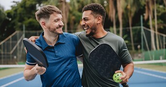 Twee mensen op een padelbaan met rackets en ballen