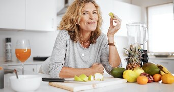 Vrouw in keuken met vers gesneden fruit en een blender