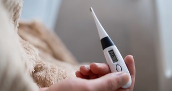 Digitale thermometer in een hand die 36,1 graden Celsius aangeeft