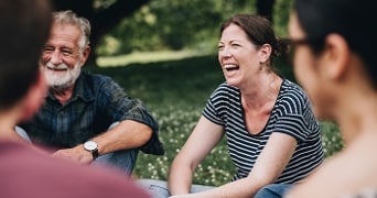 Groep mensen zit samen buiten op het gras in een gesprek