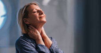 Persoon in blauwe kleding met handen rond de nek, gezicht is onscherp gemaakt.