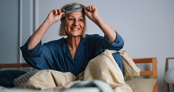 Persoon in slaapkleding plaatst een oogmasker voor het slapengaan.