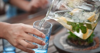 Vers water met citroen en munt wordt ingeschonken in een glas