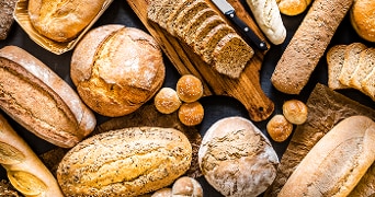 Verschillende soorten brood en broodjes op een houten tafel.